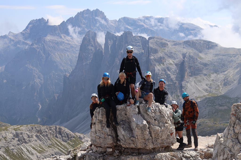 People sitting on the rock at the summit of Torre di Toblin (Toblinger Knoten) towers, Italian Dolomites