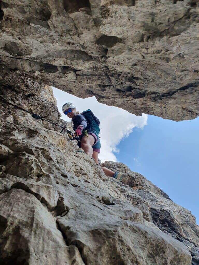 Woman climbing the chimney of Via Ferrata Cesare Piazzetta in the Sella Dolomites