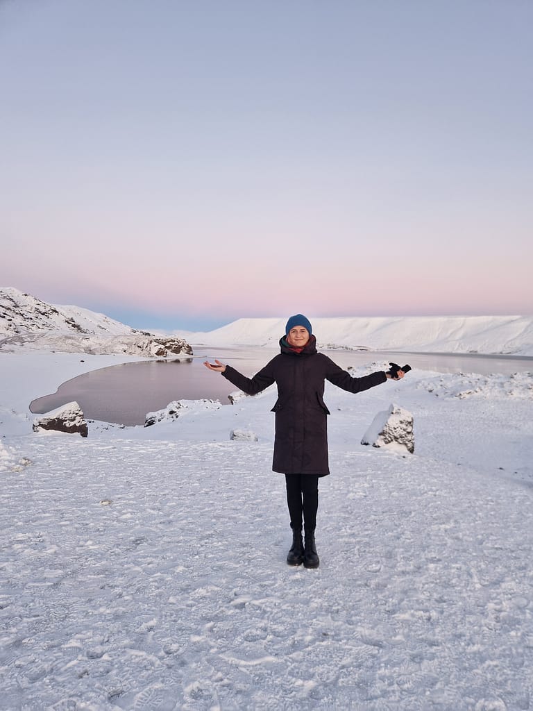 Woman in front of Kleifarvatn lake in Iceland with beautiful winter sunset colours