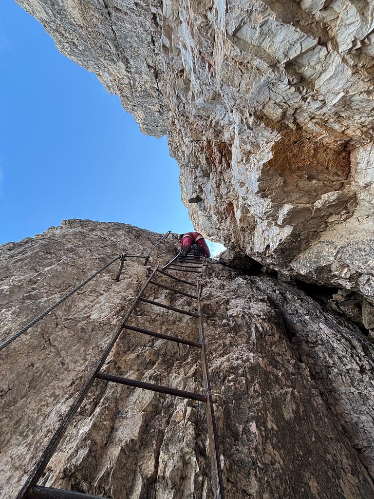 I person climbing ladders of the via ferrata delle Scallette on the Torre di Toblin towers, Italian Dolomites