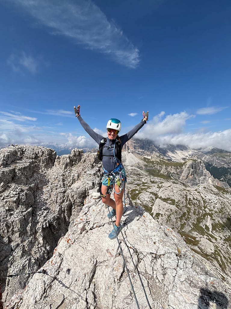 Woman at the summit Torre di Toblin towers, Italian Dolomites